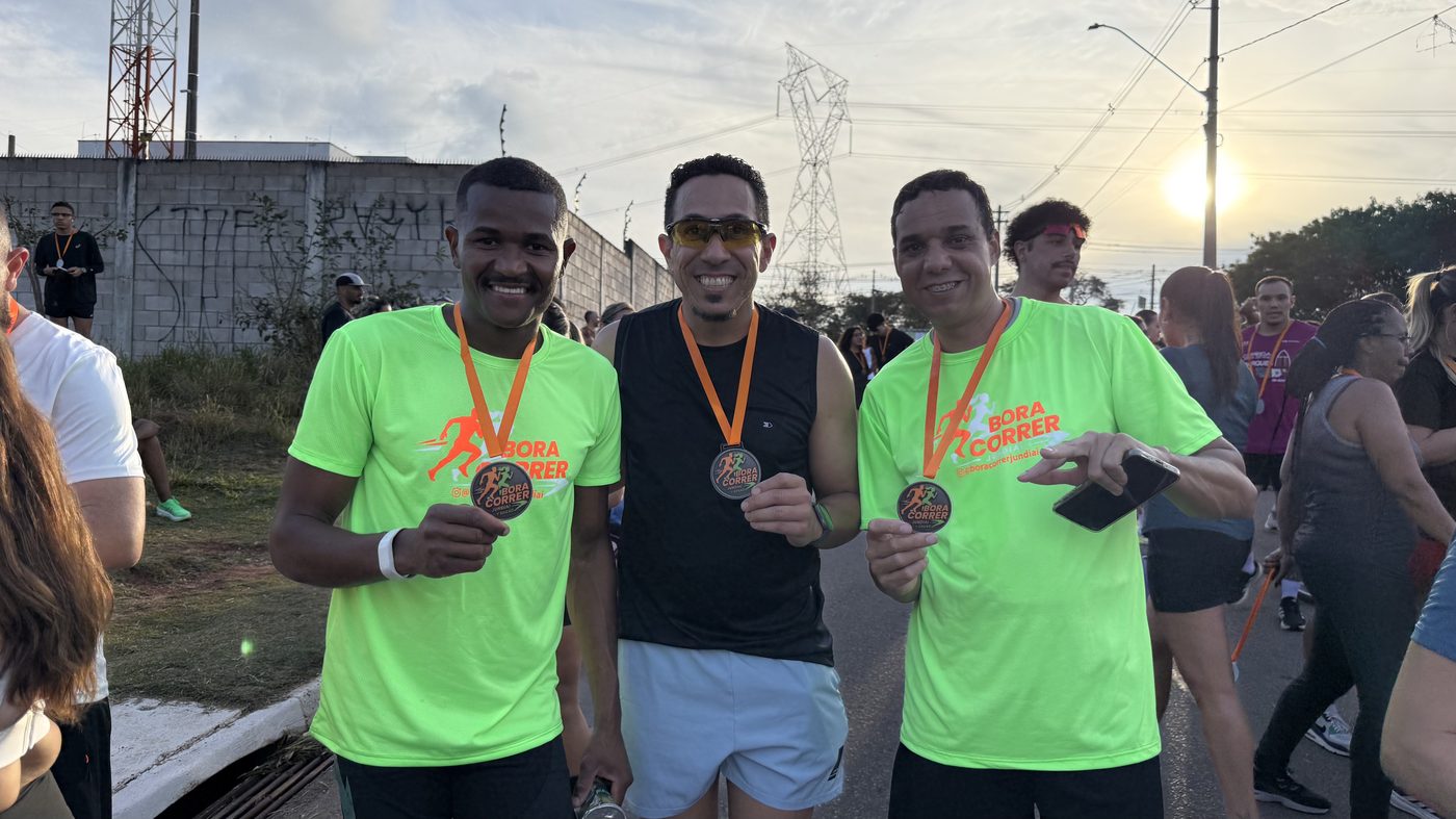 Três participantes exibindo suas medalhas de conclusão